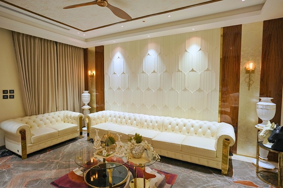 Formal living room with ivory chesterfield sofas and backlit wall panelling by HOH Luxe